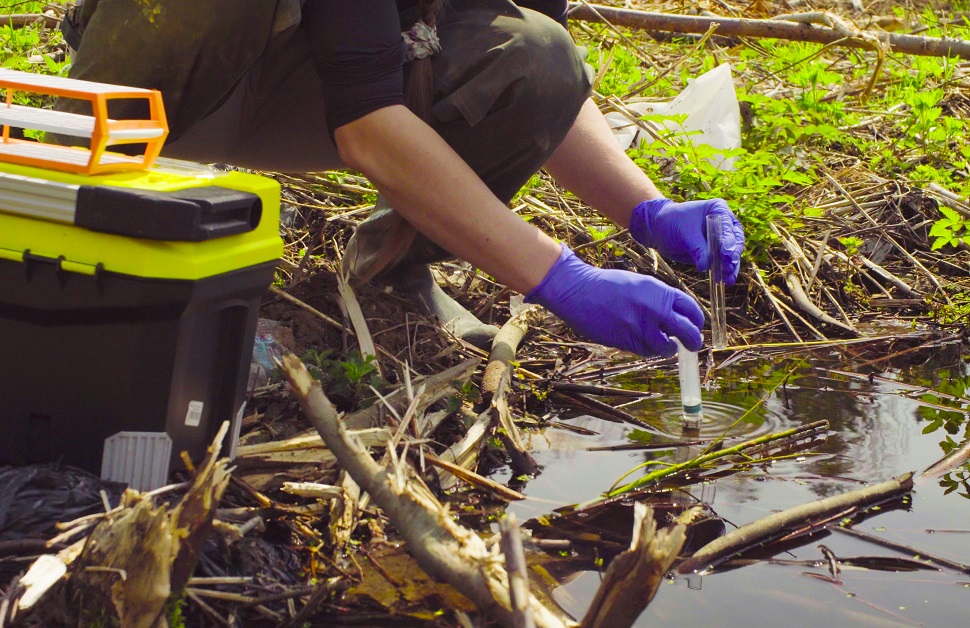 an ecologist taking water samples from a pond