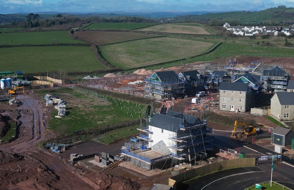 a view of a residential development being built directly next to green belt land