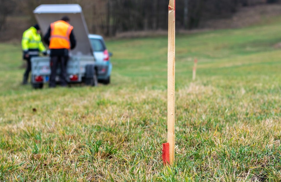A team of land surveyors tracking underground utilities using wooden posts