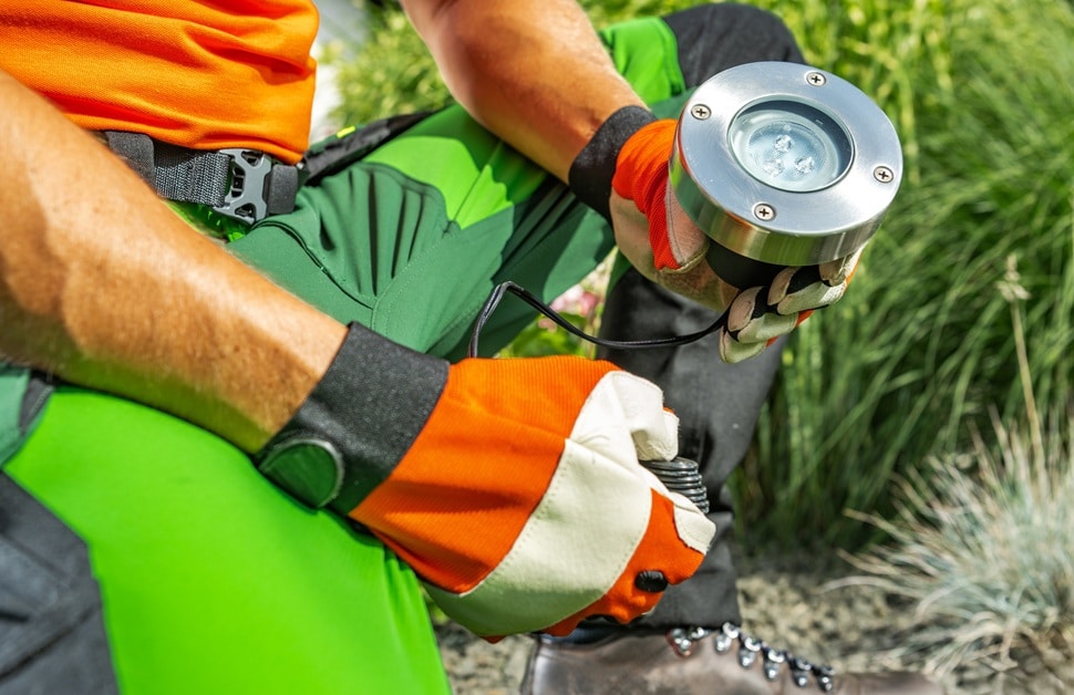 A lighting technician installing an energy-efficient and compliant outdoor light in the exterior area of a new-build development