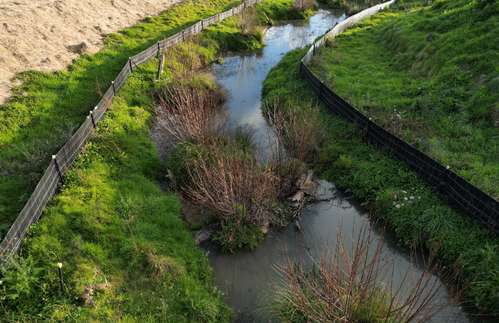 Two sets of wildlife fencing at either side of a river on a development site